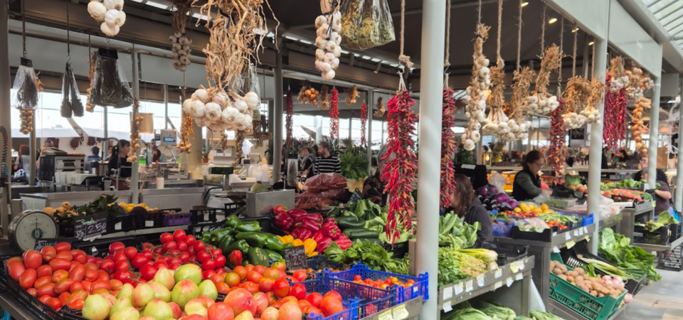 Bancas do mercado do bolhão com frutas, legumes e alho pendurados num mercado coberto