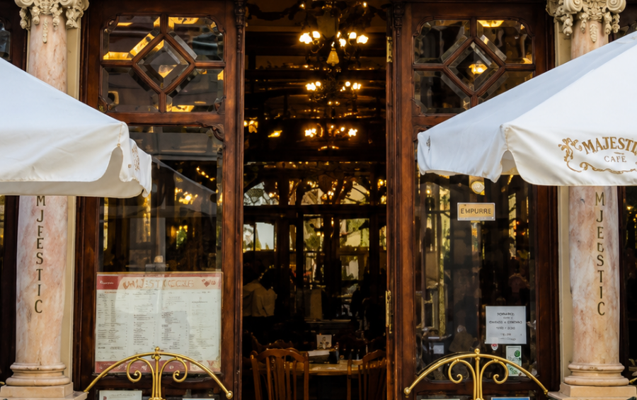Entrada ornamentada do Majestic Café, com letreiro dourado e esplanada à porta